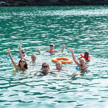 Group swimming and waving in a turquoise bay on the SYB Nicaragua Surf Camp trip