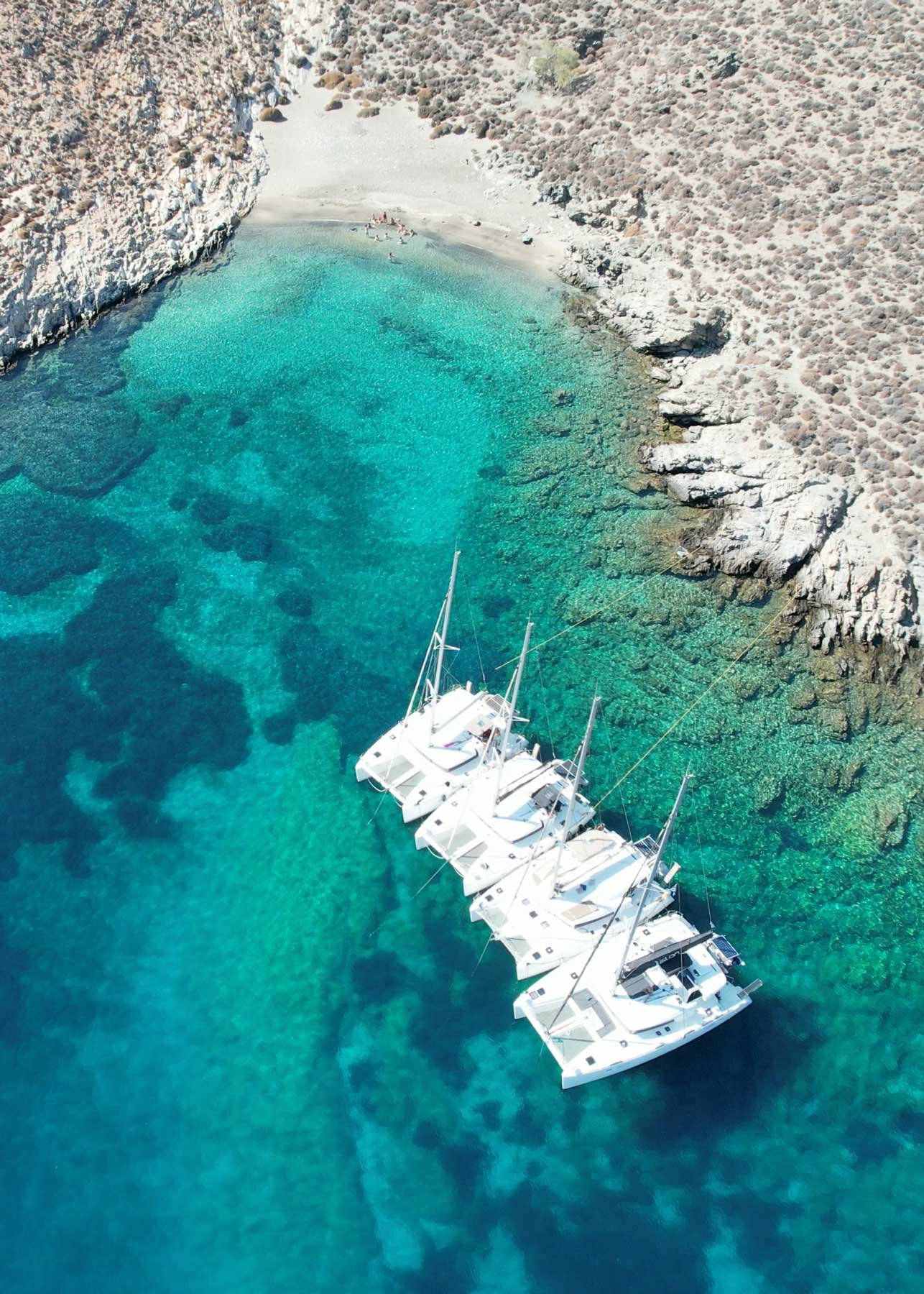 An SYB catamaran anchored in a turquoise cove from above