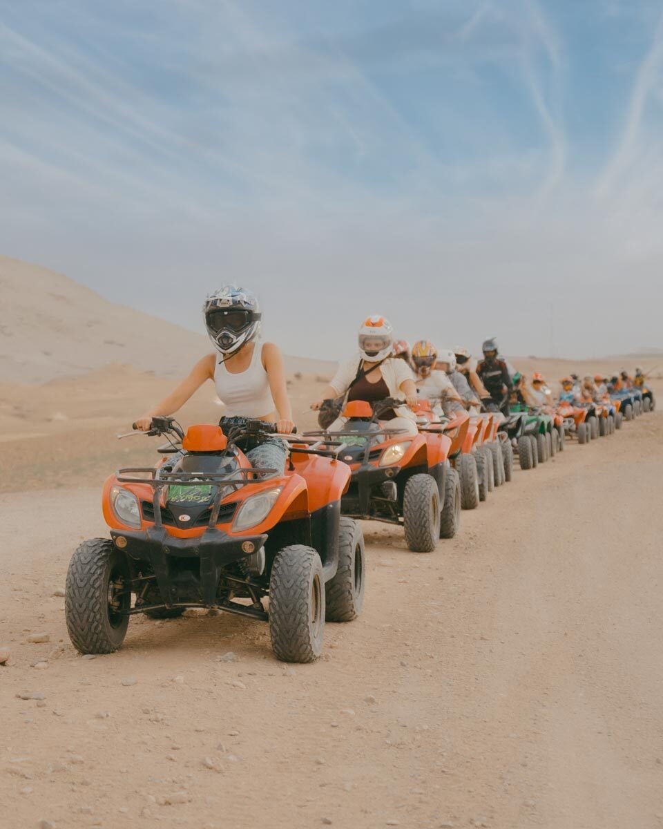 A line of SurfYogaBeer guests riding ATVs across the Sahara