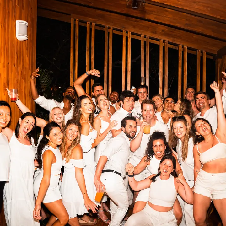 The whole SYB crew dressed in white with arms in the air at the white party on the SYB Nicaragua trip