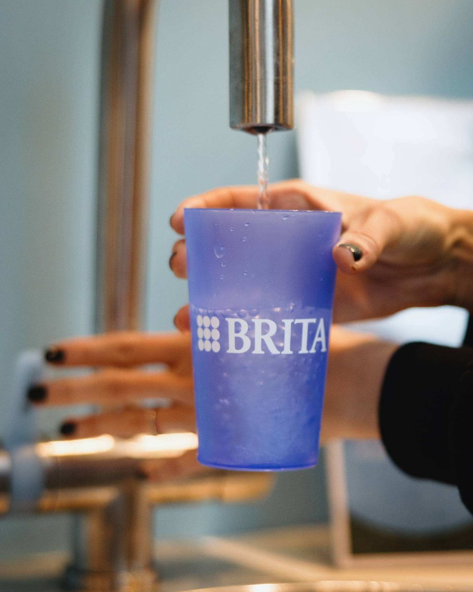 A visitor fills a BRITA cup with filtered water from a tap
