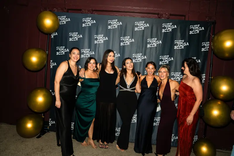 Friends in gowns lined up at the photo wall