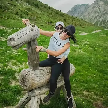Two hikers climbing on a wooden horse sculpture beside the trail on the SYB Dolomites trip