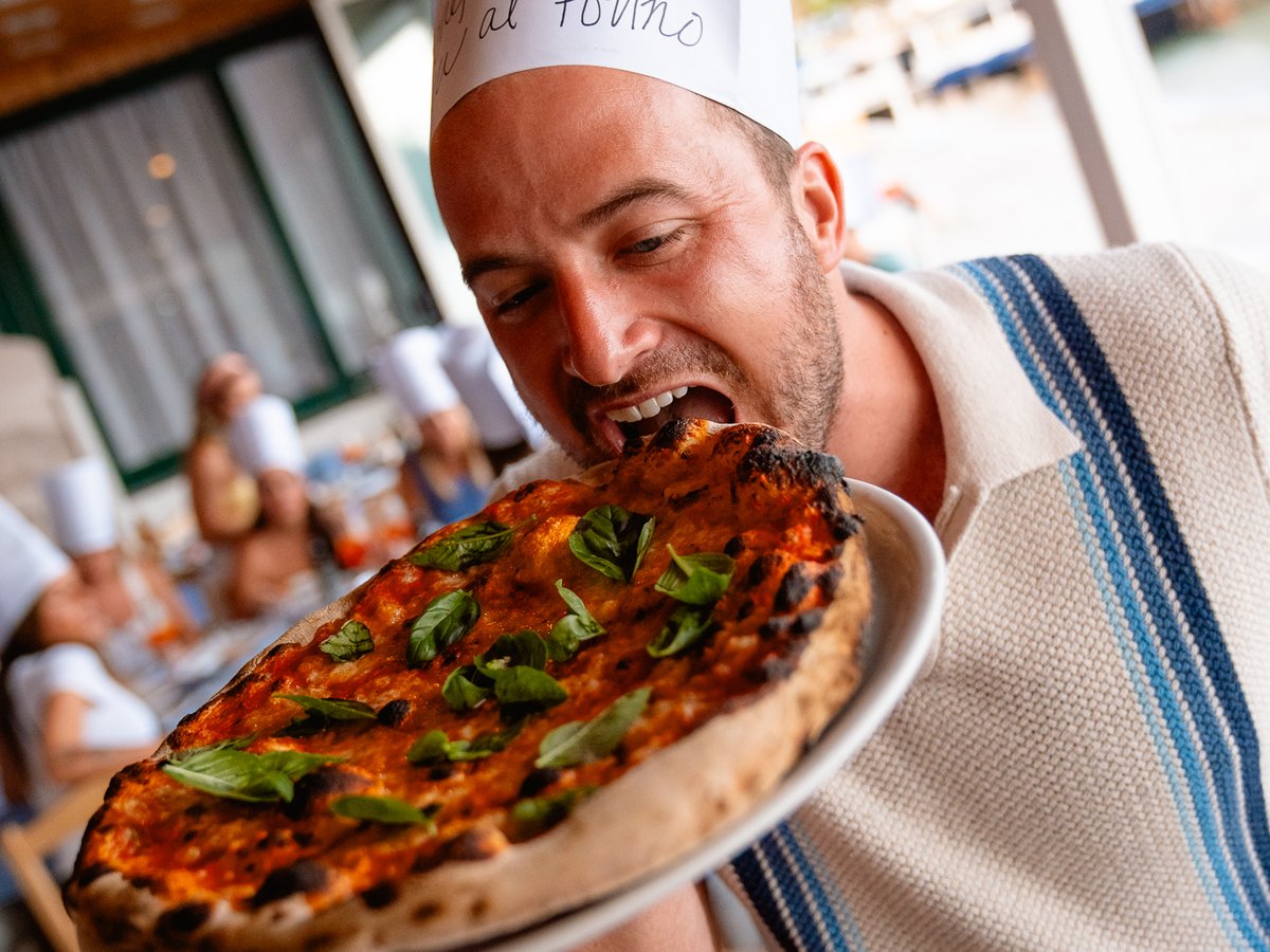 SurfYogaBeer guest in a chef hat biting into the pizza he made on the Amalfi Coast