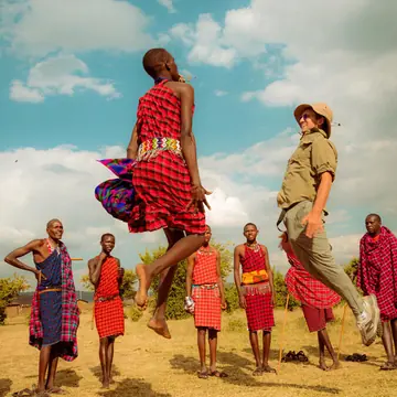 A guest jumping alongside a Maasai warrior in mid air on the SYB Kenya trip
