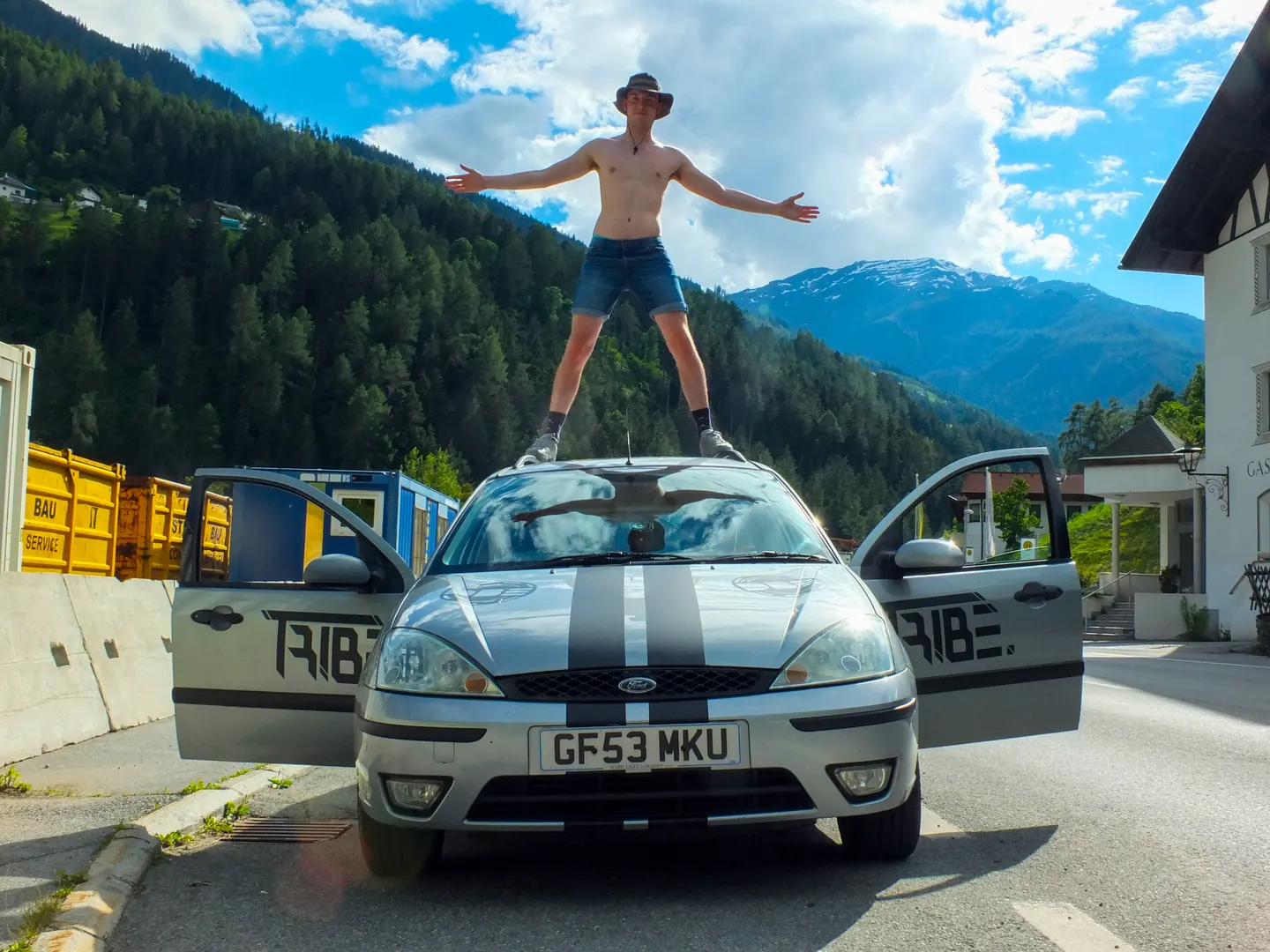 Participant standing on a car with arms wide open during the Dash to Dubrovnik with Hardest Adventures.