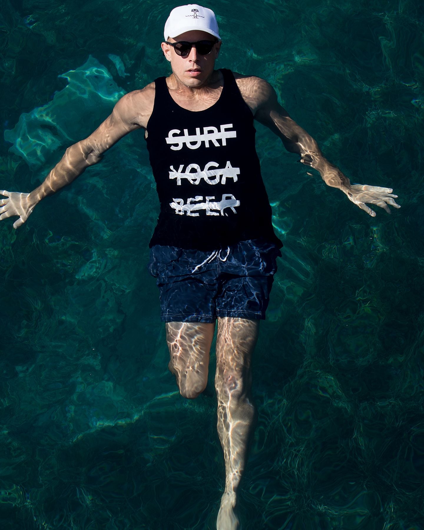 SYB crew member floating in clear water in Croatia, wearing the black OG cross-out tank