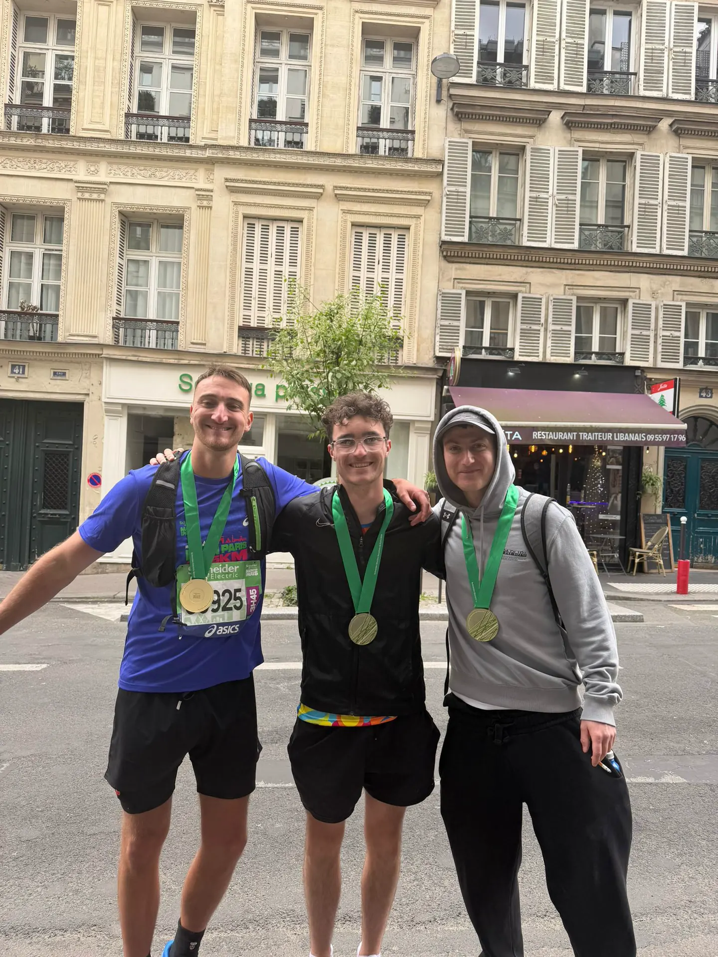 Hardest Adventures runners showing their finisher medals after the Paris Marathon.