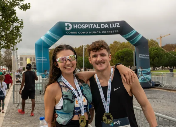 Two university student runners celebrating with their medals having just completed the Hardest Adventures EDP Lisbon Half Marathon.