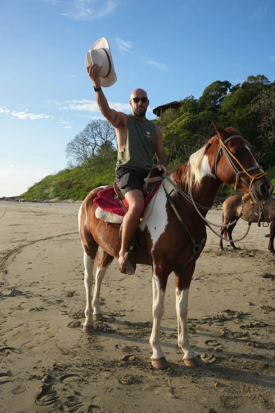 A rider on horseback waving a hat on the beach in Nicaragua