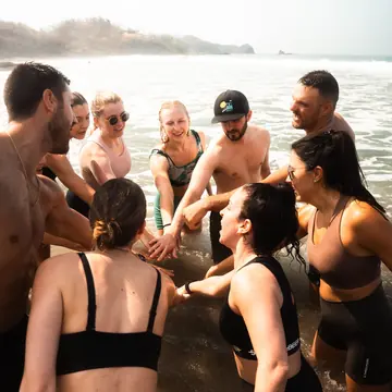 Group huddle with hands in, knee deep in the ocean on the SYB Nicaragua Surf Camp trip