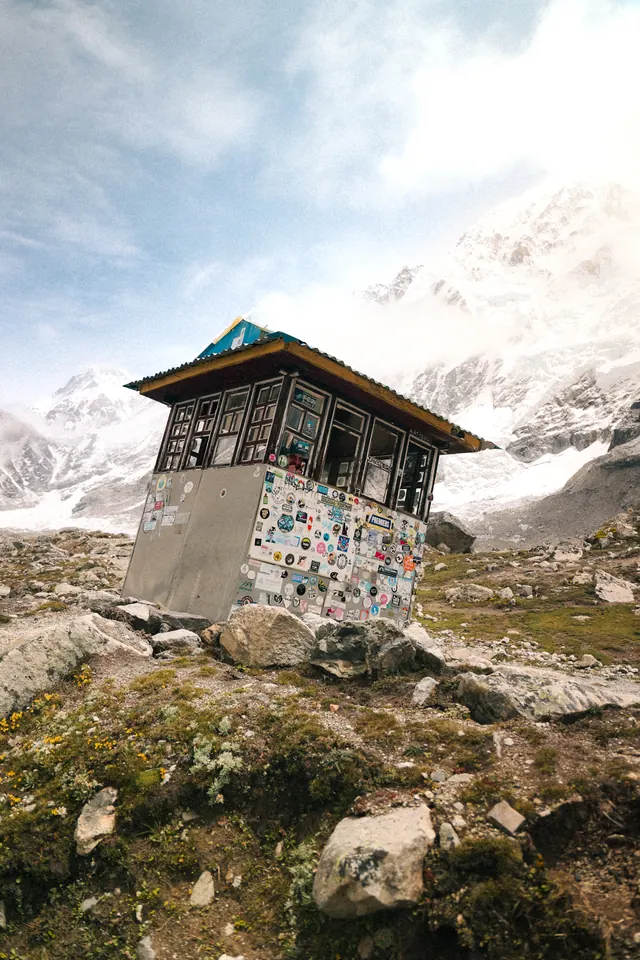 A tiny sticker-covered hut on the Khumbu moraine with the snow face behind, on the final push to Base Camp