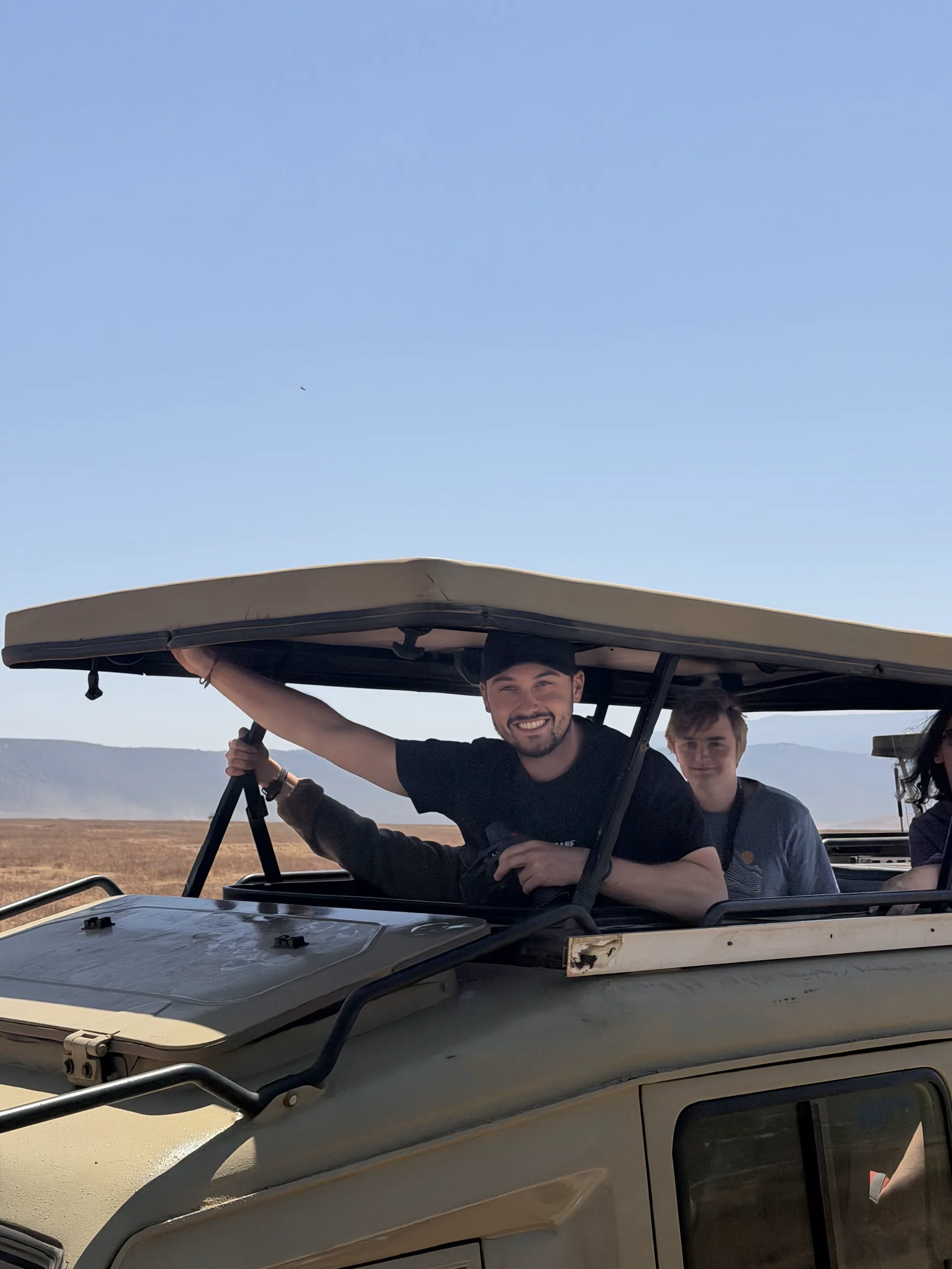 Smiling participants under the pop-up roof of a safari jeep in the Ngorongoro Crater on the Kilimanjaro safari extension.