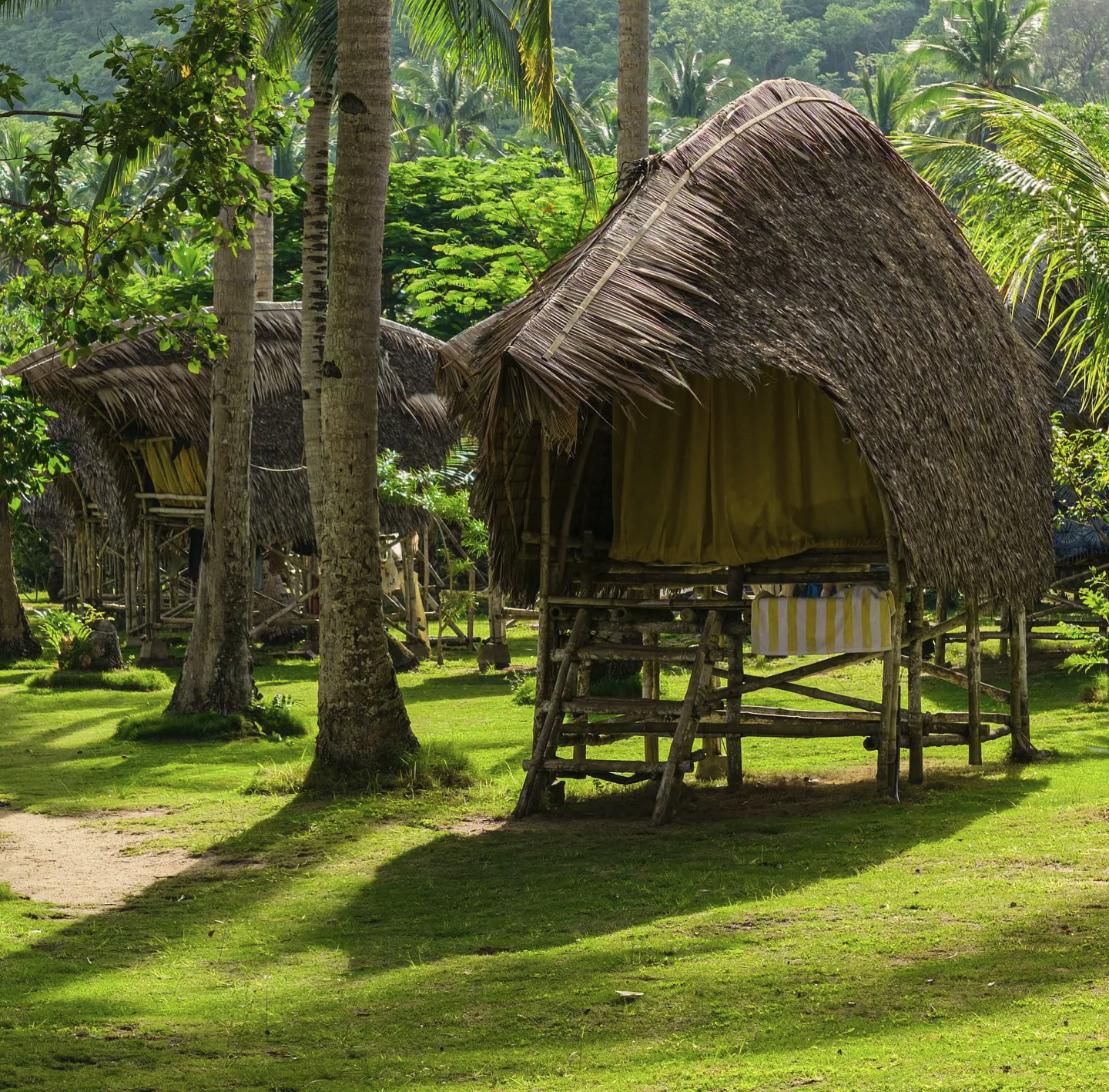 A raised bamboo sleeping hut with a thatched roof at an island camp in Palawan