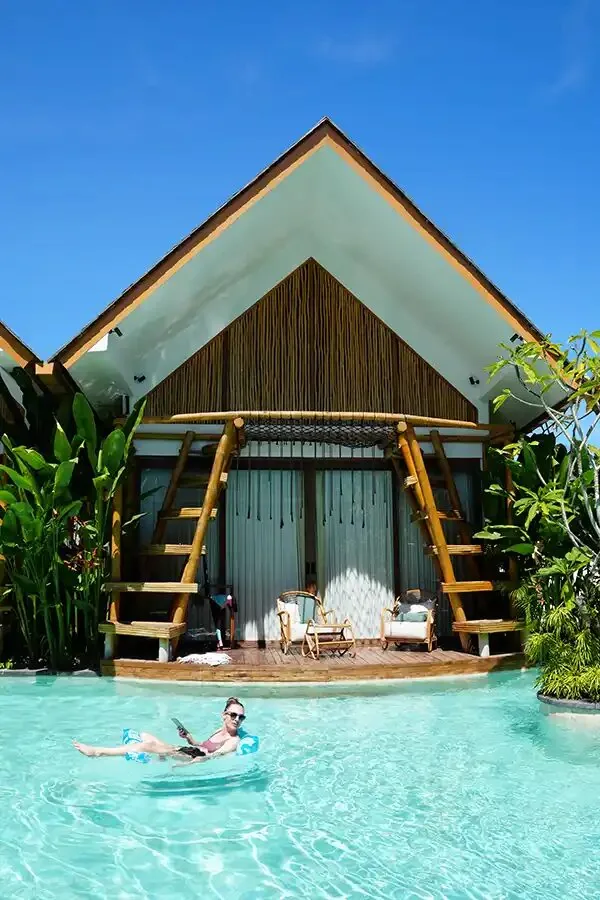A traveler floating in the pool in front of a villa at SYB's Bali retreat