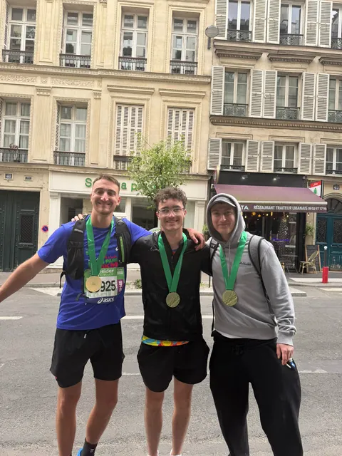 Hardest Adventures runners showing their finisher medals after the Paris Marathon.