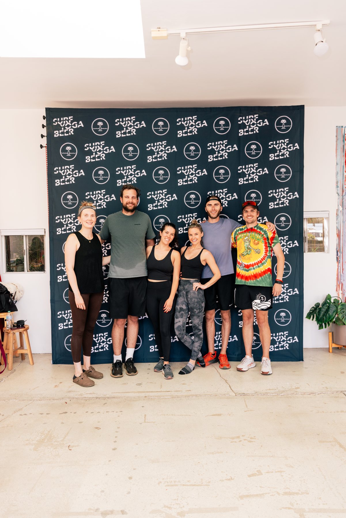 The 2025 crew at the SurfYogaBeer backdrop
