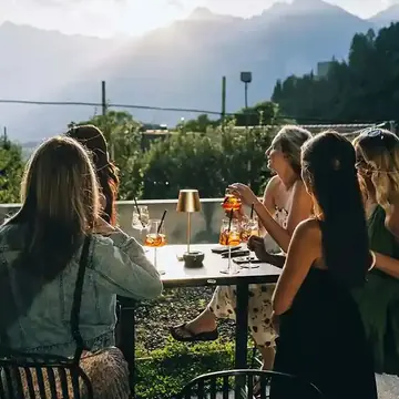Friends sharing spritzes on a terrace with a mountain view on the SYB Dolomites trip