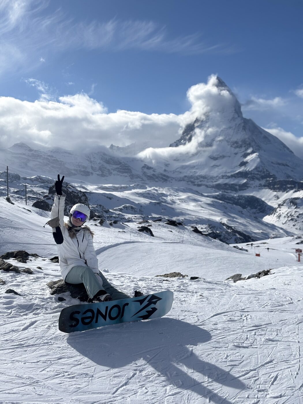 A snowboarder sitting on the snow in front of the Matterhorn