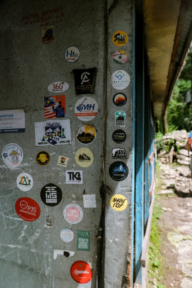 A trailside teahouse doorway covered in trekking stickers on the route to Namche Bazaar