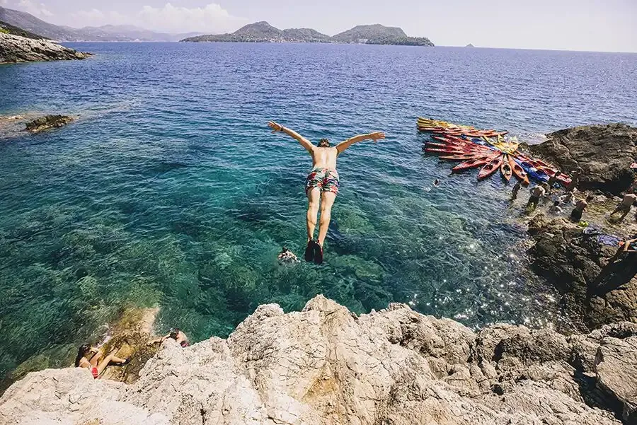 Jumping off the rocks into clear turquoise water on the SYB Croatia trip