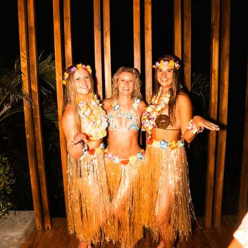 Three friends in grass skirts and flower crowns for theme night on the SYB Nicaragua trip