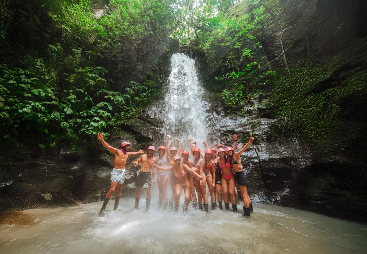 An SYB crew under a jungle waterfall in Bali