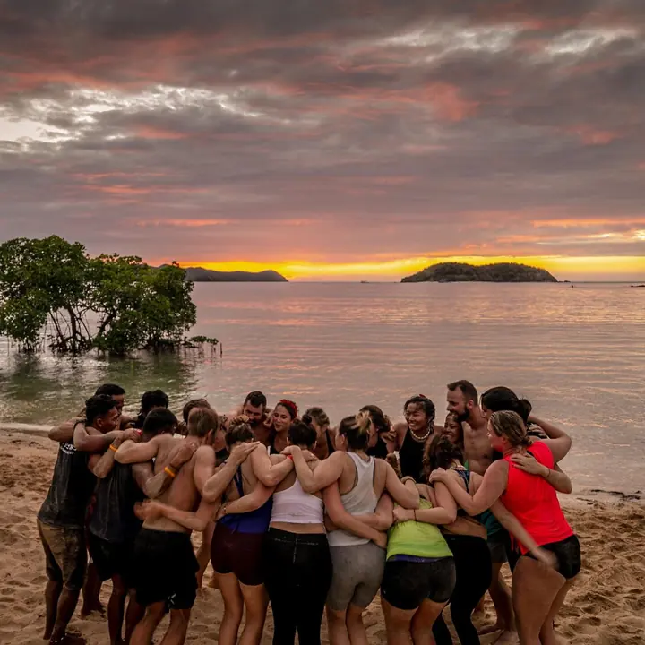 The whole group in a huddle on the beach at sunset on the SYB Philippines trip
