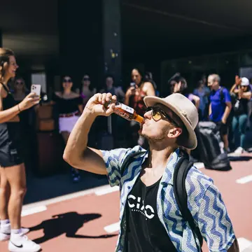 Crew member leaning back to finish a drink while friends film on the SYB Dolomites trip