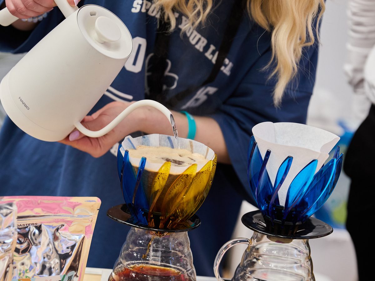 A visitor pours water from a gooseneck kettle into a pour-over dripper