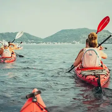 Kayaking across the bay with green hills behind on the SYB Croatia trip