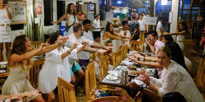 Long table dinner with everyone dressed in white reaching across the table on the SYB Philippines trip
