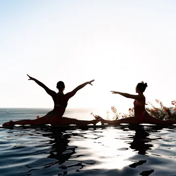 Yoga silhouettes on the edge of the infinity pool