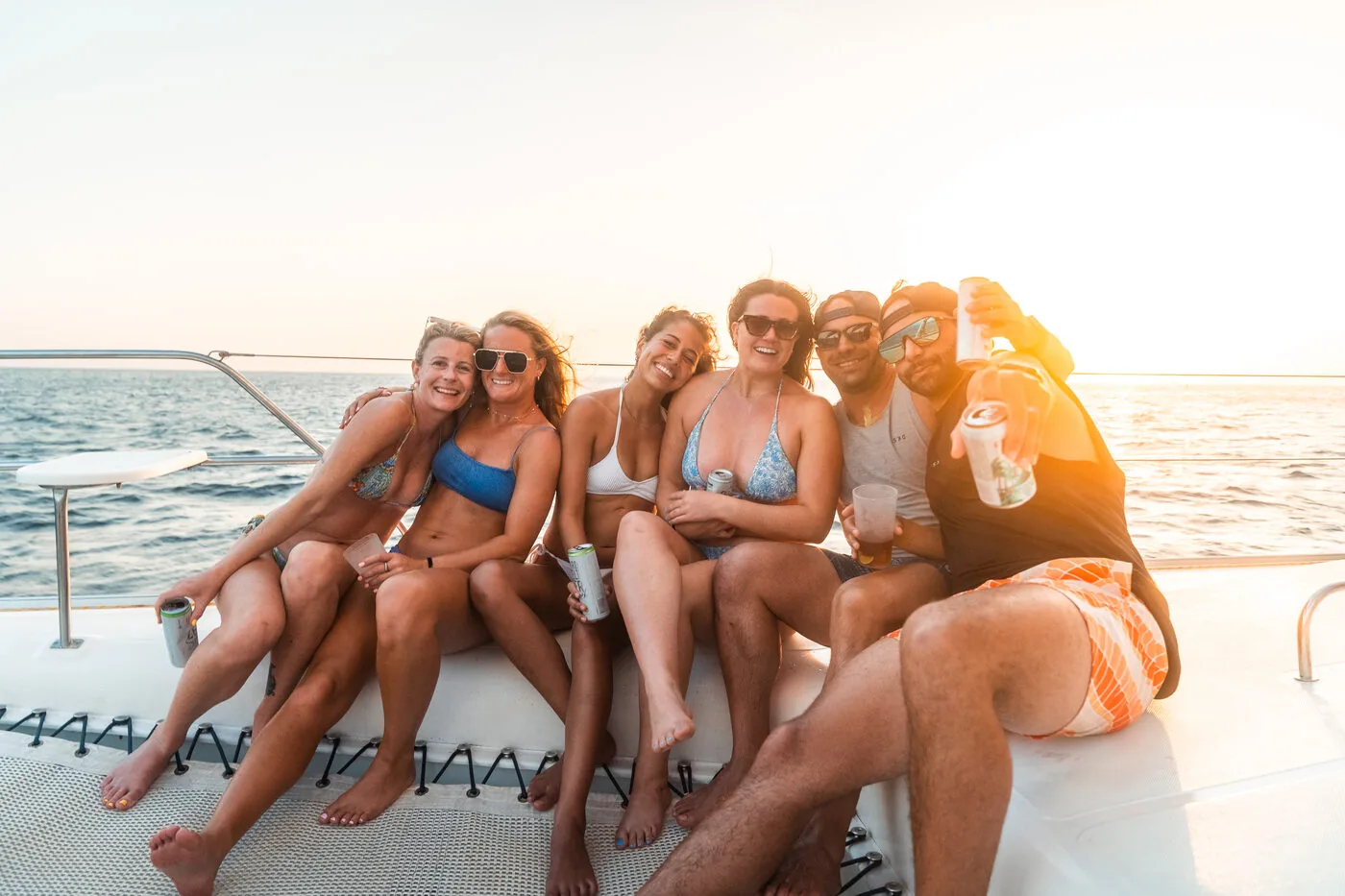 Six friends sitting together on the deck of a catamaran at sunset off the coast of Nicaragua