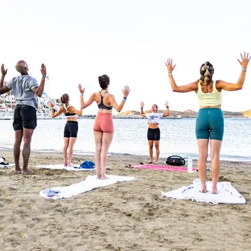 Yoga on the beach with arms raised to the sky on the SYB Greece trip