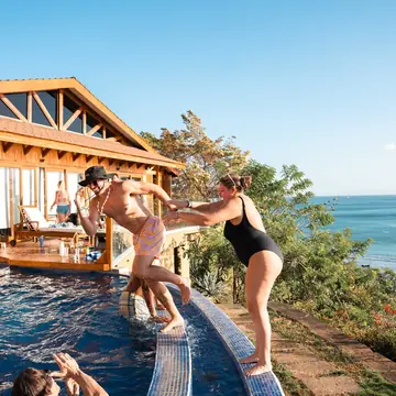 Friends pushing each other into the infinity pool above the ocean on the SYB Nicaragua trip