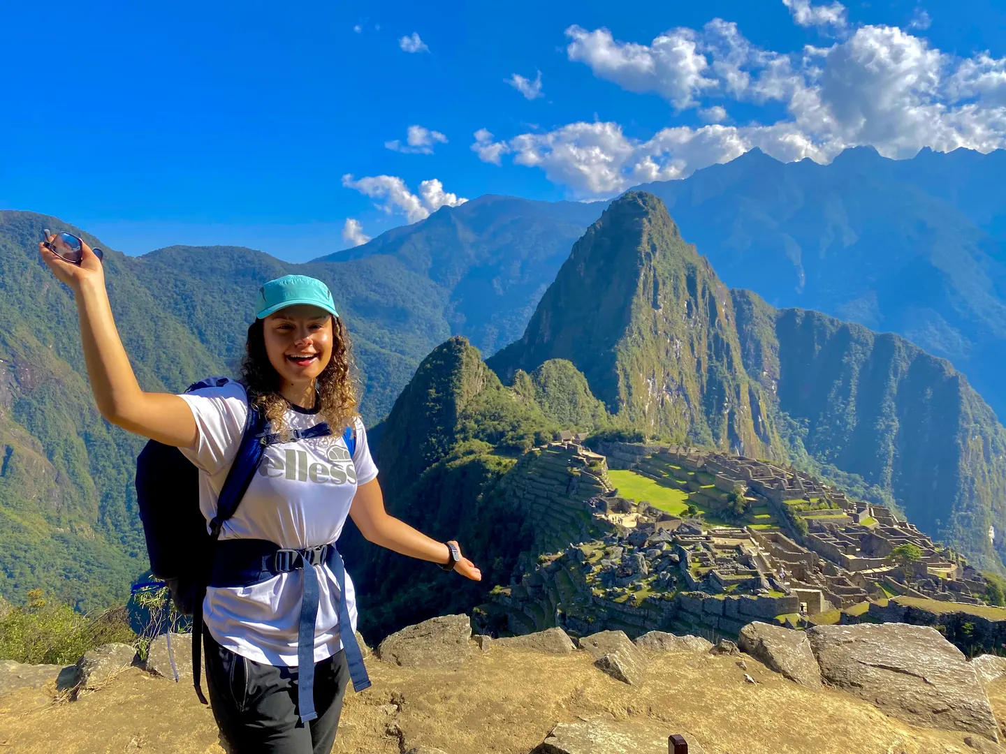 Hardest Adventures trekker standing with arms raised in celebration overlooking Machu Picchu.