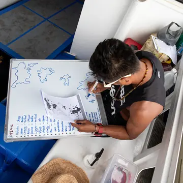 Drawing a map of the islands on a whiteboard on the boat on the SYB Philippines trip