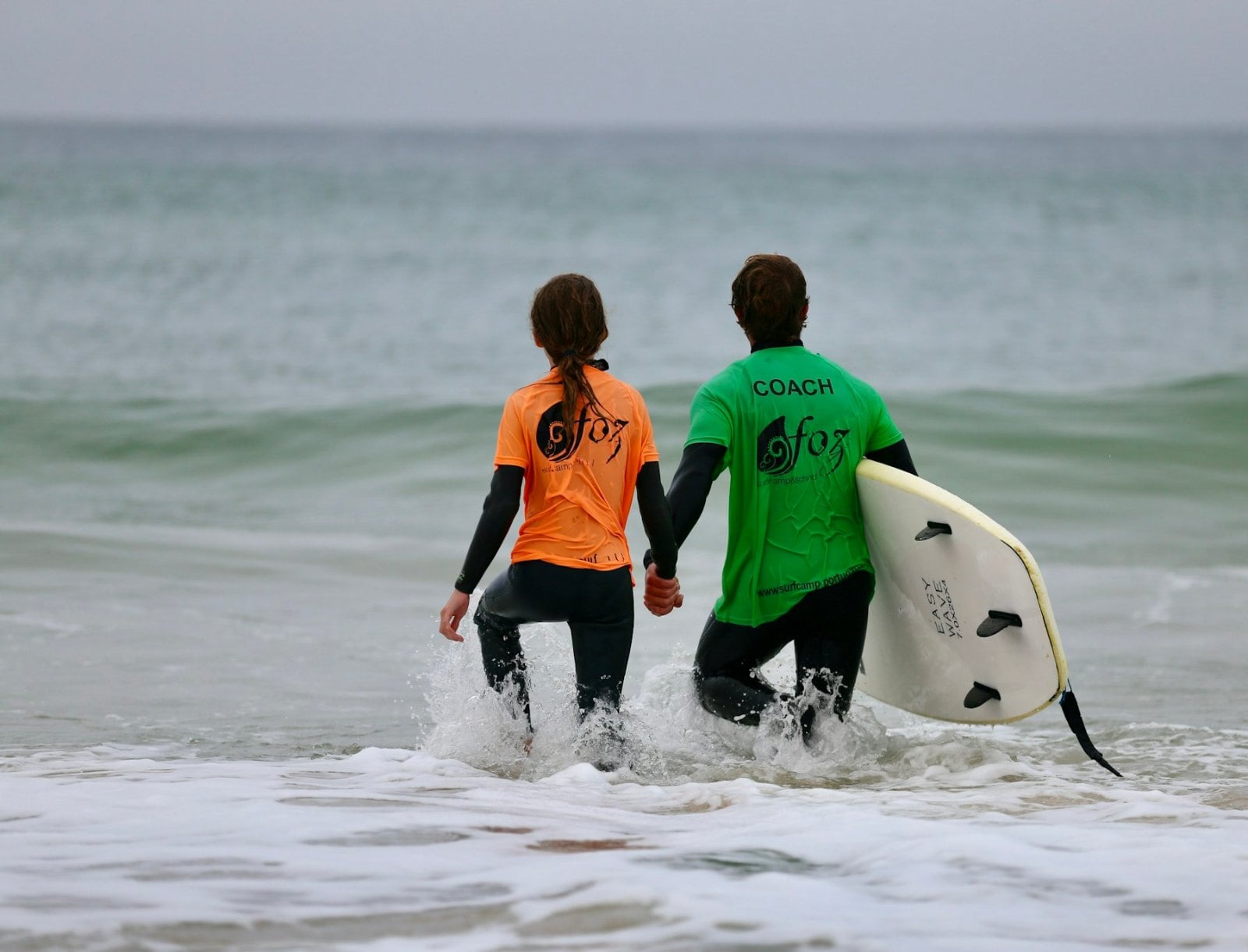 Two surfers carrying boards down to the water