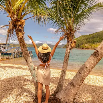 Arms up between two palm trees on the beach on the SYB Philippines trip