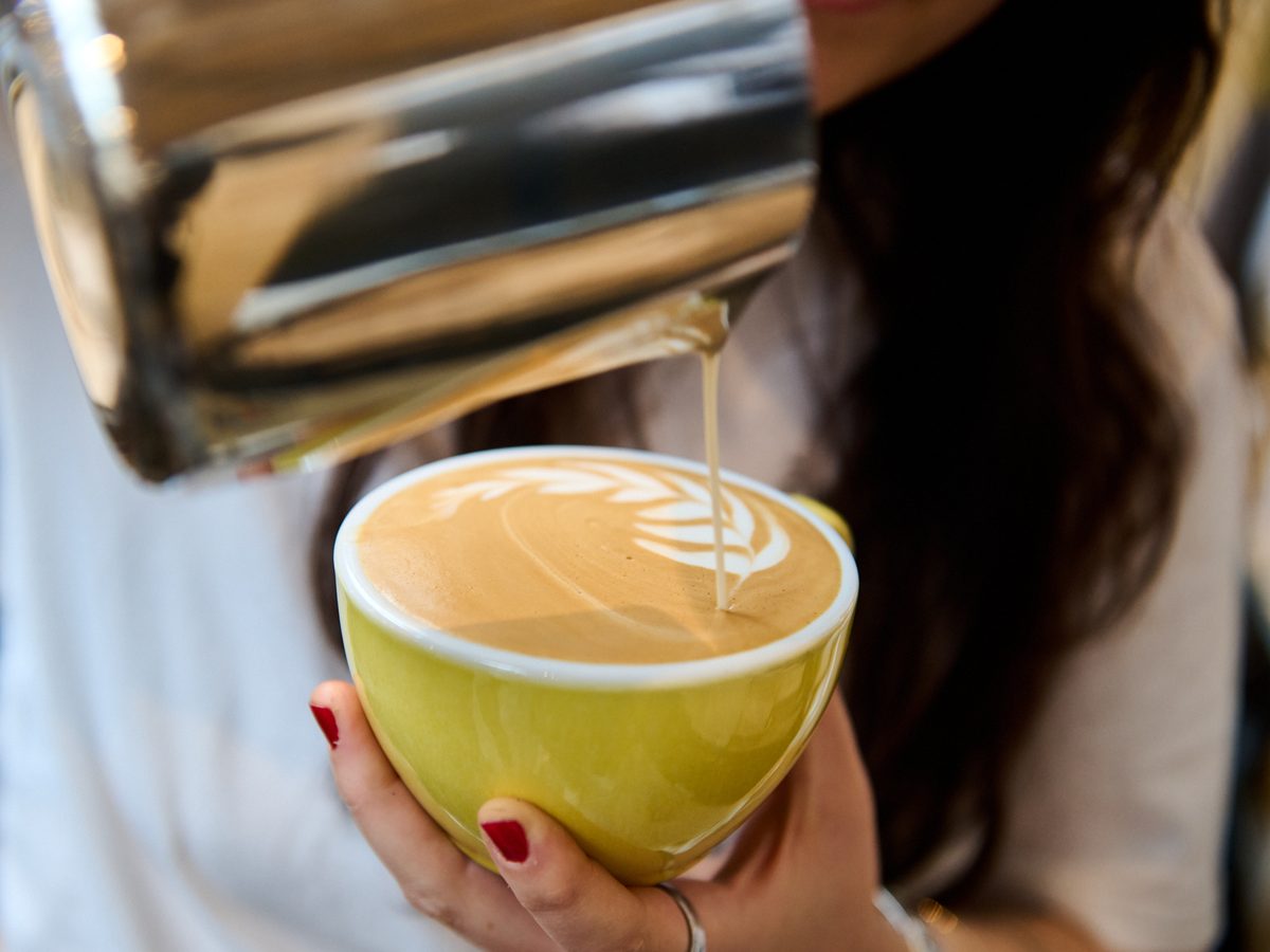 Milk is poured into a cappuccino to finish a latte art rosetta