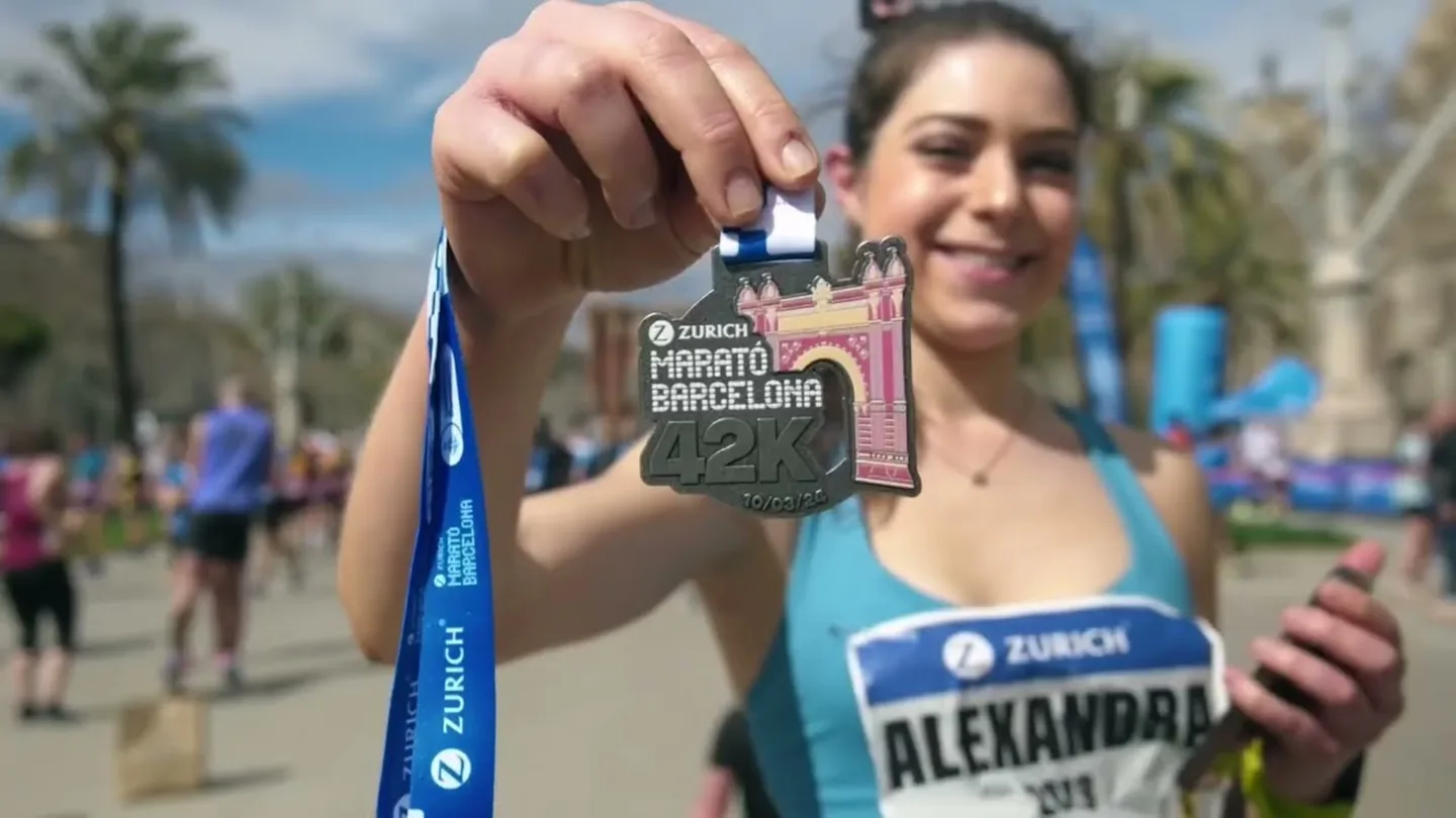 Smiling finisher holding up her Barcelona Marathon medal.