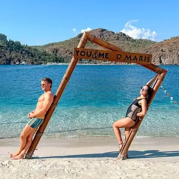 Two friends leaning on a wooden frame on a beach with turquoise water on the SYB Turkey trip