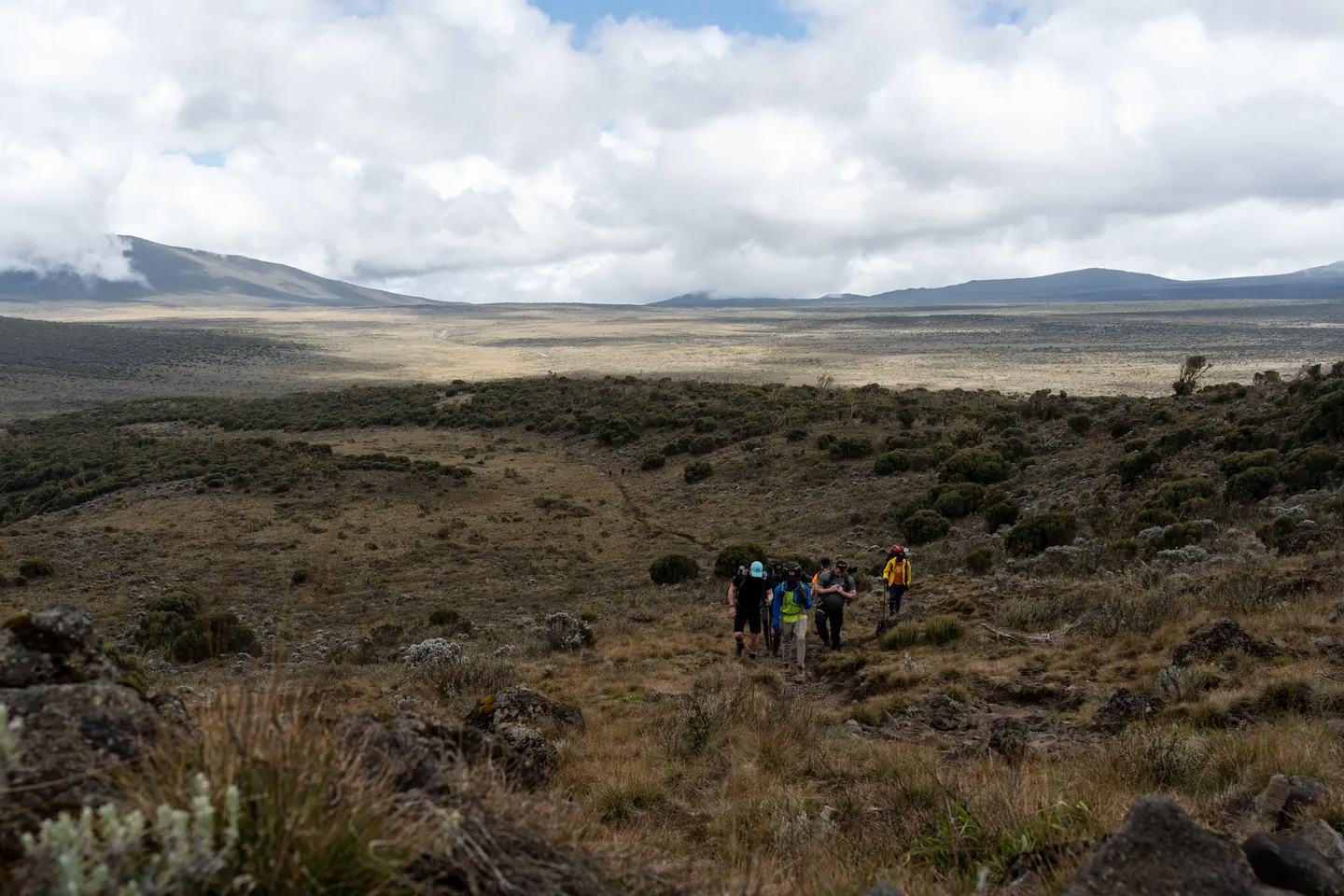 Lone trekker silhouetted against the sun below Kibo peak on Mount Kilimanjaro with Hardest Adventures.