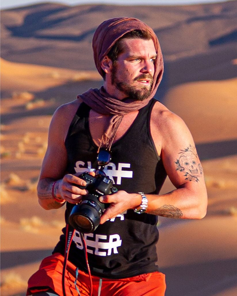 SYB crew member with a camera in the desert, wearing the black cross-out tank