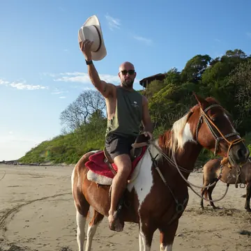 Rider waving a hat in the air on horseback on the beach on the SYB Nicaragua Surf Camp trip