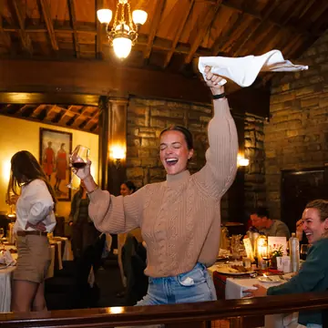 Guest swinging a napkin over her head at dinner in the lodge on the SYB Kenya trip