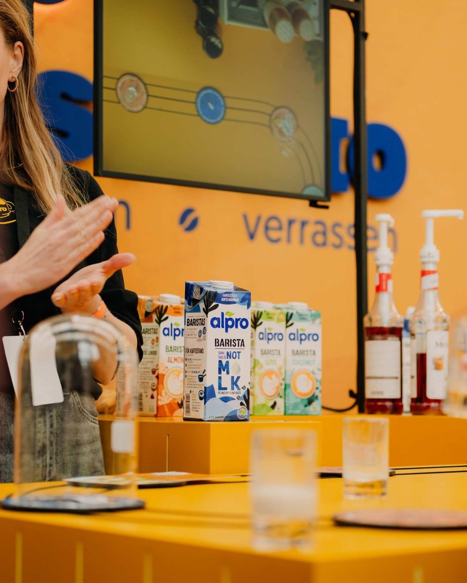 Alpro barista cartons lined up on a bright yellow stand