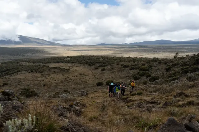 Lone trekker silhouetted against the sun below Kibo peak on Mount Kilimanjaro with Hardest Adventures.