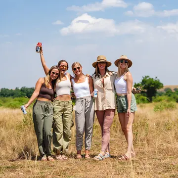 Five friends in safari hats standing in the grassland on the SYB Kenya trip